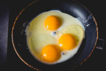 Brightly colored eggs sizzle in a frying pan, showcasing perfect yolks ready for breakfast delight