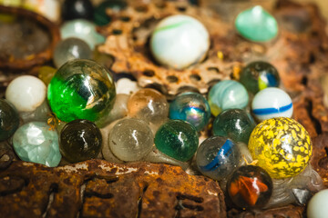 Colorful glass marbles scattered on a rustic surface under soft lighting creating a nostalgic and vivid atmosphere