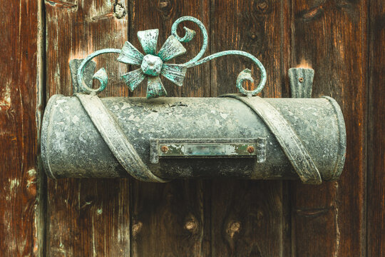 Rustic mailbox adorned with ornate metalwork against a weathered wooden backdrop exuding timeless charm