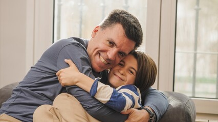 Father and son embracing on sofa, showing love and affection