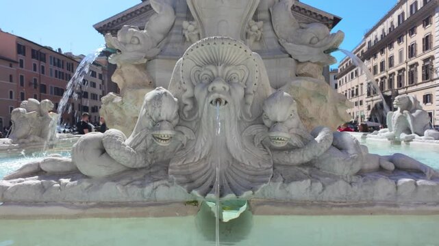 Baroque marble fountain detail featuring bearded river god face pouring water amid dolphins and marine creatures in iconic piazza navona, rome