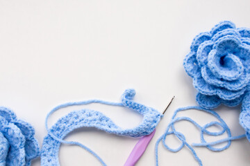 Handmade blue crochet flowers with yarn and hook on white background