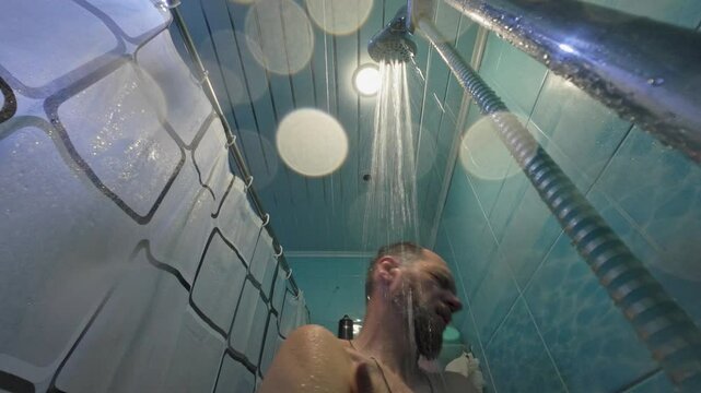 bearded middle aged man washing himself under shower in bathroom, hygiene and body care