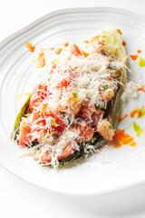 Grilled romaine lettuce salad topped with diced tomatoes, shredded cheese, and herbs, drizzled with vibrant orange and green sauces, served on a white plate.