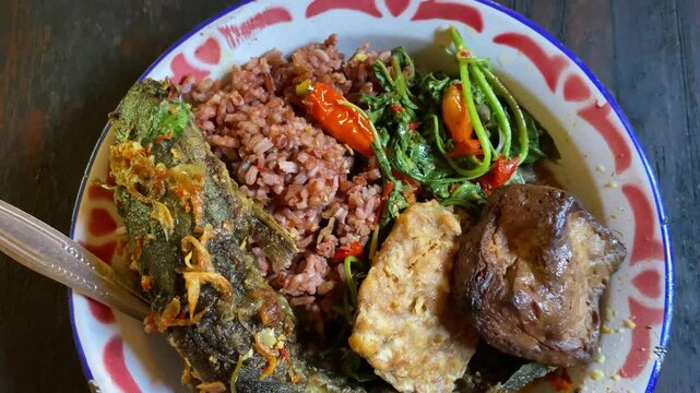 4k video footage of Mangut Lele is authentic javanese food from Yogyakarta and Solo. Traditional catfish dishes are full of spices and spicy in a plate on wooden table.