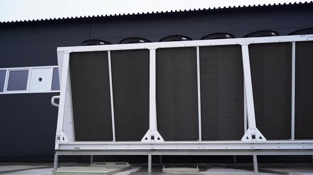 Chillers unit for industrial equipment cooling down by manufacturing facility building. Modern vent duct used at black production plant