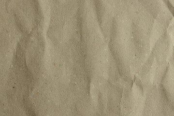 Close-up of a crumpled, light brown kraft paper texture. Its earthy tone