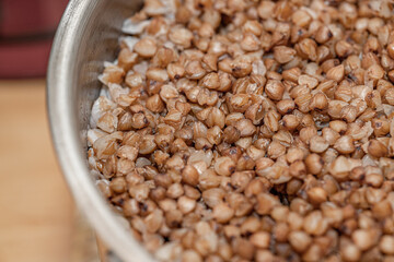 Plate with tasty buckwheat porridg.Boiled buckwheat porridge in ceramic pot on wooden background.