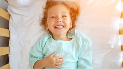 Happy child smiling and lying on bed in hotel room