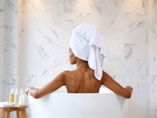 Woman relaxing in bathtub with towel on head