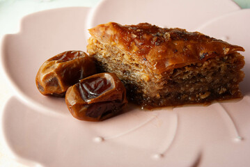Traditional Turkish baklava dessert with dates, elegantly served on a pink plate.