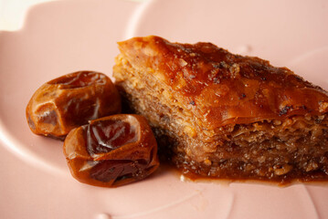 Traditional Turkish baklava dessert with dates, elegantly served on a pink plate.