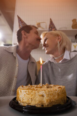 Senior couple kissing at birthday party with cake and candle