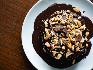 top view cake covering with dark chocolate ganache sauce with crushed cashew nuts and chocolate chunk