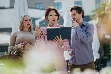 A diverse group of business people engage in a collaborative meeting outdoors in an urban setting,...