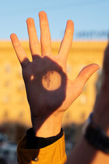 Hand illuminated by sunset with botanical shadow projection. Observing the sun. Projection image of the Sun on palm