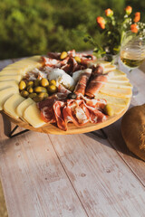 Catering on a wooden board on a rustic table, meat, olives, cheese, and a drink as an appetizer