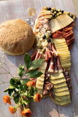 Catering on a wooden board on a rustic table, meat, olives, cheese, and a drink as an appetizer