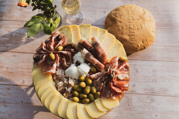 Catering on a wooden board on a rustic table, meat, olives, cheese, and a drink as an appetizer