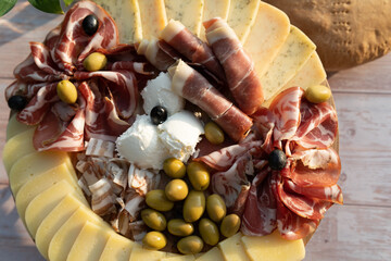 Catering on a wooden board on a rustic table, meat, olives, cheese, and a drink as an appetizer