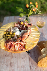 Catering on a wooden board on a rustic table, meat, olives, cheese, and a drink as an appetizer