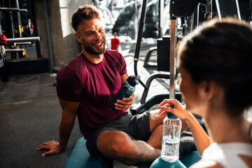 Young Couple Resting and Smiling in Modern Gym Environment