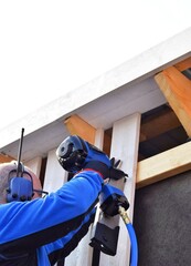 Man using pneumatic stapler, nail gun for wooden board, driving metal nails and staples