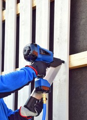 Man using pneumatic stapler, nail gun for wooden board, driving metal nails and staples.
