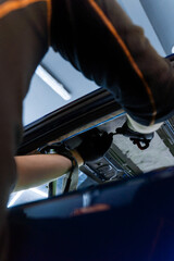 Black gloves ensure grip and safety while performing insulation adjustments. Technician working under the roof liner performs structural repairs using precision hand tools.