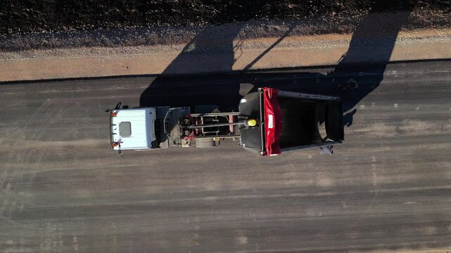 Empty tipper truck moving along a newly surfaced road