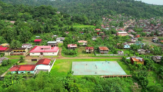Aerial view of children playing ball and riding bikes with Ribeira Afonso Village in the background. S&atilde;o Tom&eacute;,Africa