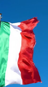 A majestic italian flag with crisp green, pure white, red stripes, silk fabric, waving gracefully against a perfectly clear, bright cerulean blue sky, illuminated by high-key natural daylight.