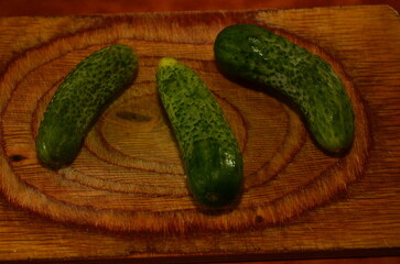 Three ripe cucumbers on a light background of a cutting board