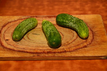 Three ripe cucumbers on a light background of a cutting board