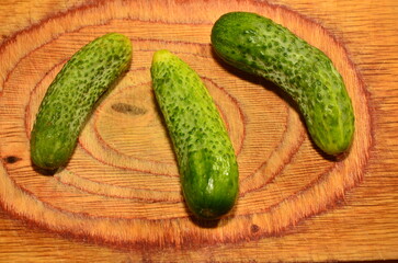 Three ripe cucumbers on a light background of a cutting board