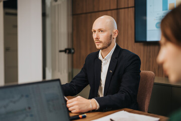 A sharp, focused professional in a collaborative workspace demonstrates a serious demeanor while contributing during a discussion.