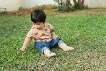 Asain baby boy sitting and playing on green grass