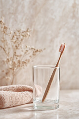Toothbrush with pink bristles in a transparent glass in the bathroom
