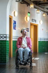 Thoughtful student guy in wheelchair, stop thoughtfully near lecture classrooms, reflection, gazing out of window. Accessibility in educational institutions environment for people with disabilities.