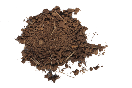 A mound of brown clumpy soil rests on a neutral surface mixed with scattered dry grass