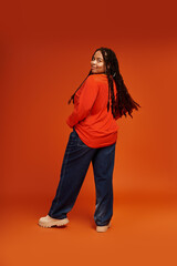 Bright and stylish portrait of a confident woman against an orange backdrop