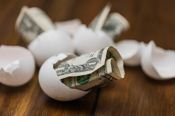 broken eggshells with one dollar bills to show increased prices on food and eggs