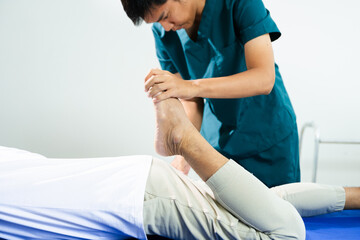 Fototapeta premium Male physiotherapist assists patient with leg and ankle stretching during rehabilitation. Medical care, joint mobility, and physical therapy