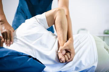 Fototapeta premium Male physiotherapist performs spine and arm adjustment therapy for patient on bed. Manual therapy, pain relief, posture alignment