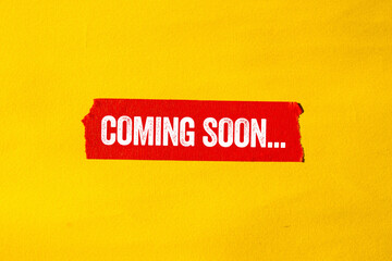 Coming soon message written on ripped torn red paper tape on yellow background. Conceptual coming...