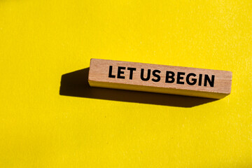 Let us begin message written on wooden block on yellow background. Conceptual let us begin symbol....