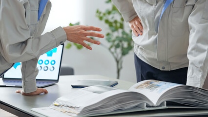 カタログを見ながら打ち合わせする作業員グループ