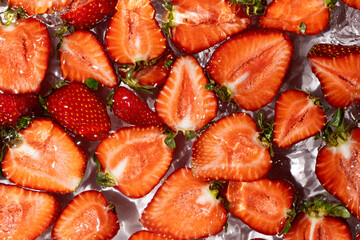Halves of fresh ripe strawberries in water, summer juicy fruit berry background.