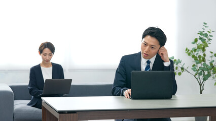 オフィスでノートパソコンを使って作業する男女ビジネスパーソンのグループ