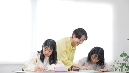 勉強する二人の女の子と女性教員